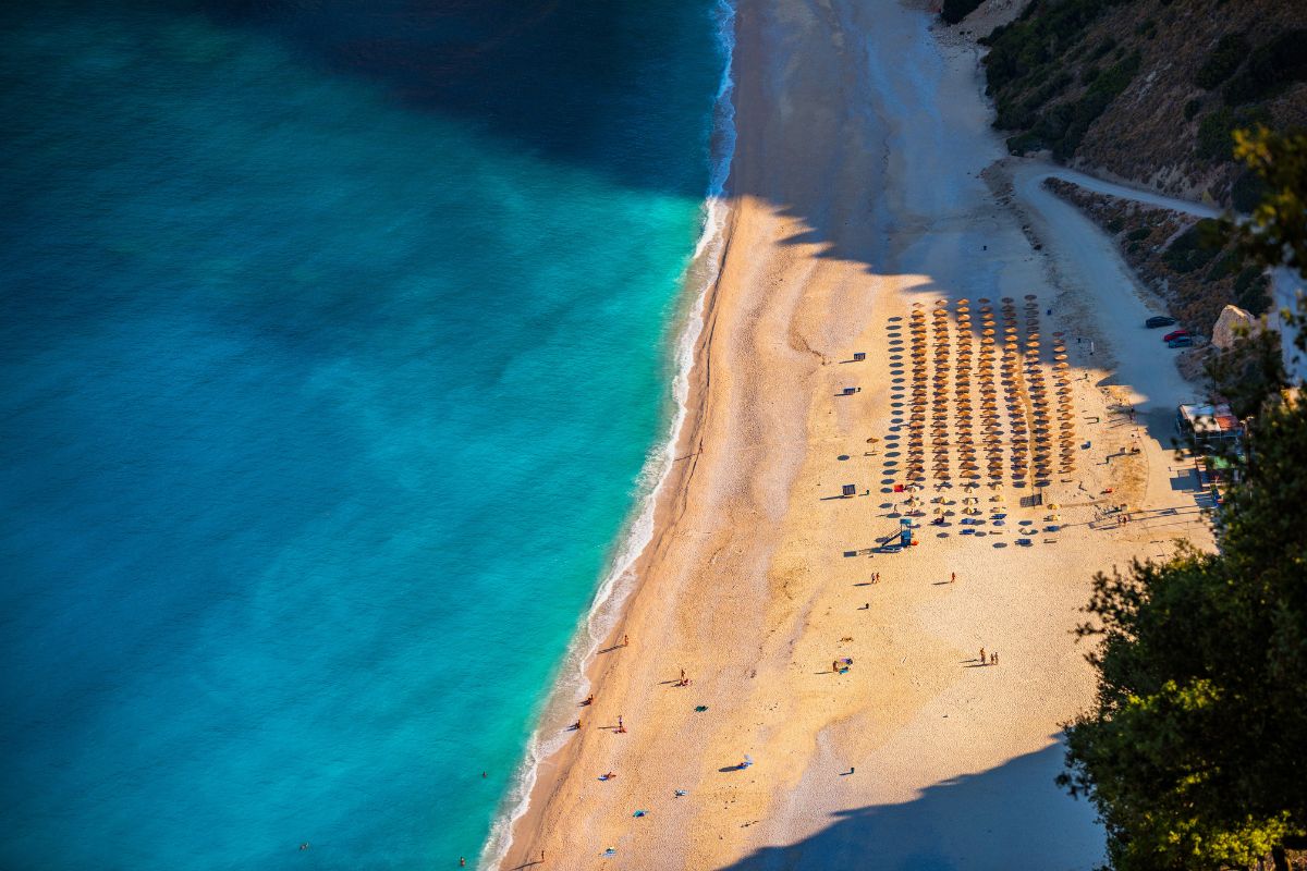 Spiaggia di Myrtos a Cefalonia, arco di ciottoli bianchi tra falesie e mare turchese