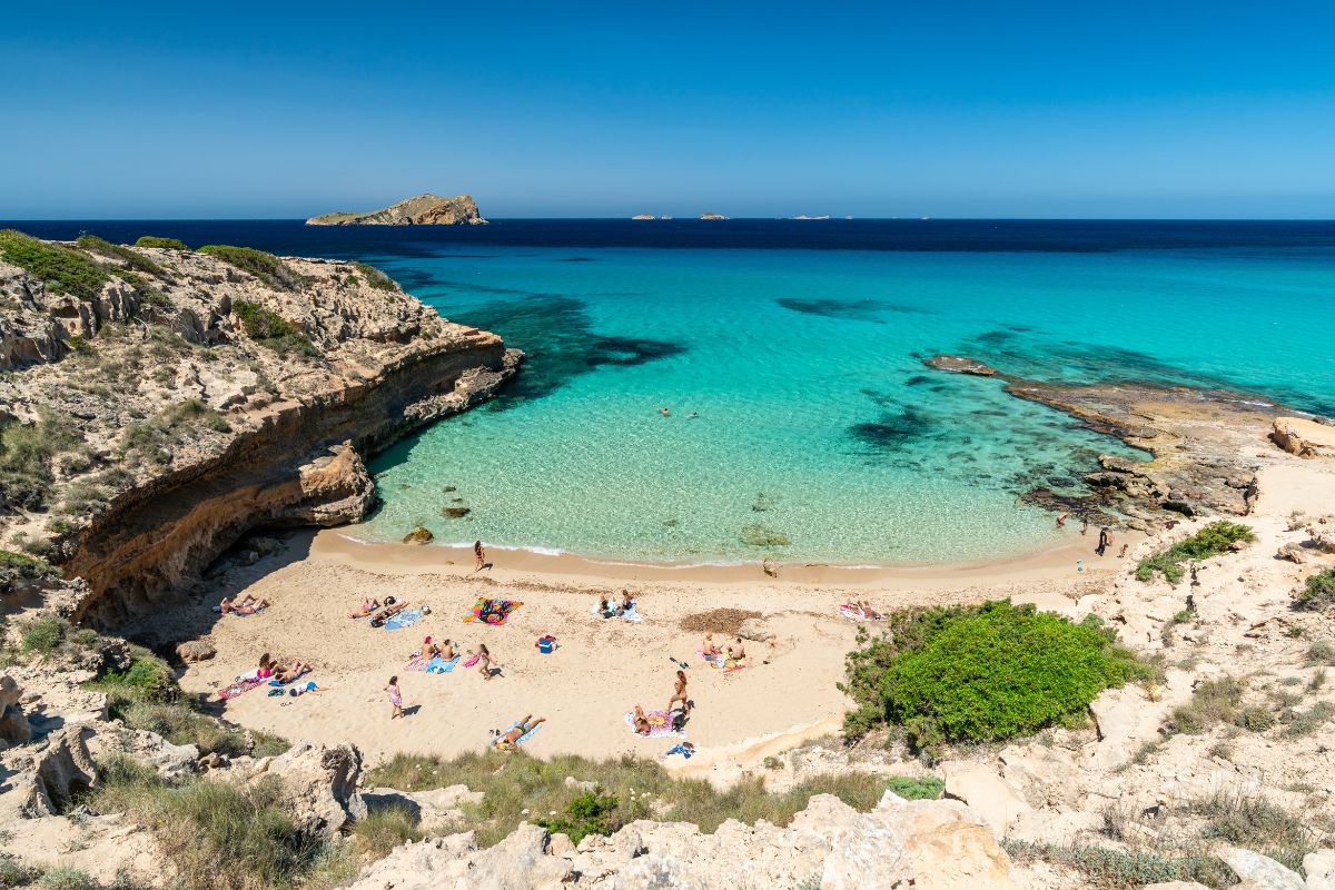 Cala Comte a Ibiza, acque turchesi trasparenti e isolotti all'orizzonte